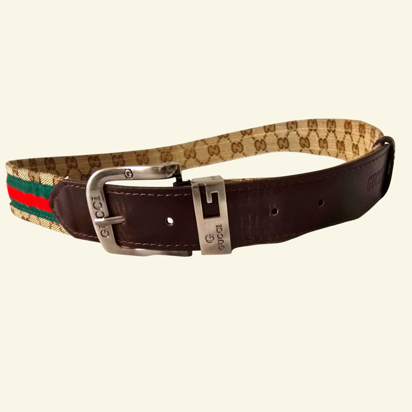 Gucci belt with brown leather strap and patterned webbing on a beige background