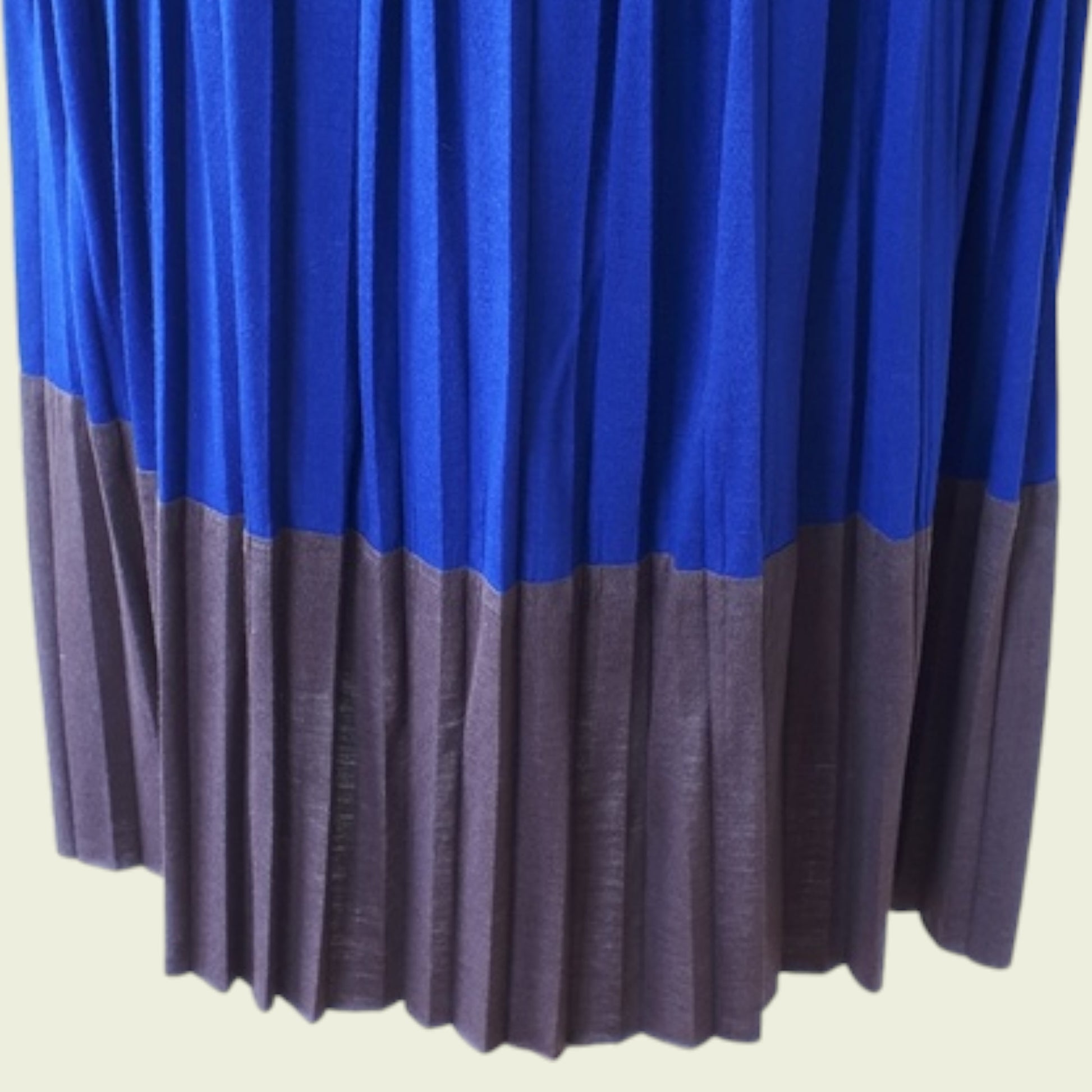 Blue and brown pleated dress on a beige background