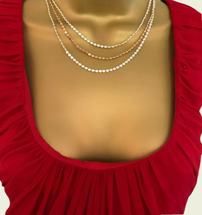 Mannequin wearing a red dress with gold necklaces on a plain background