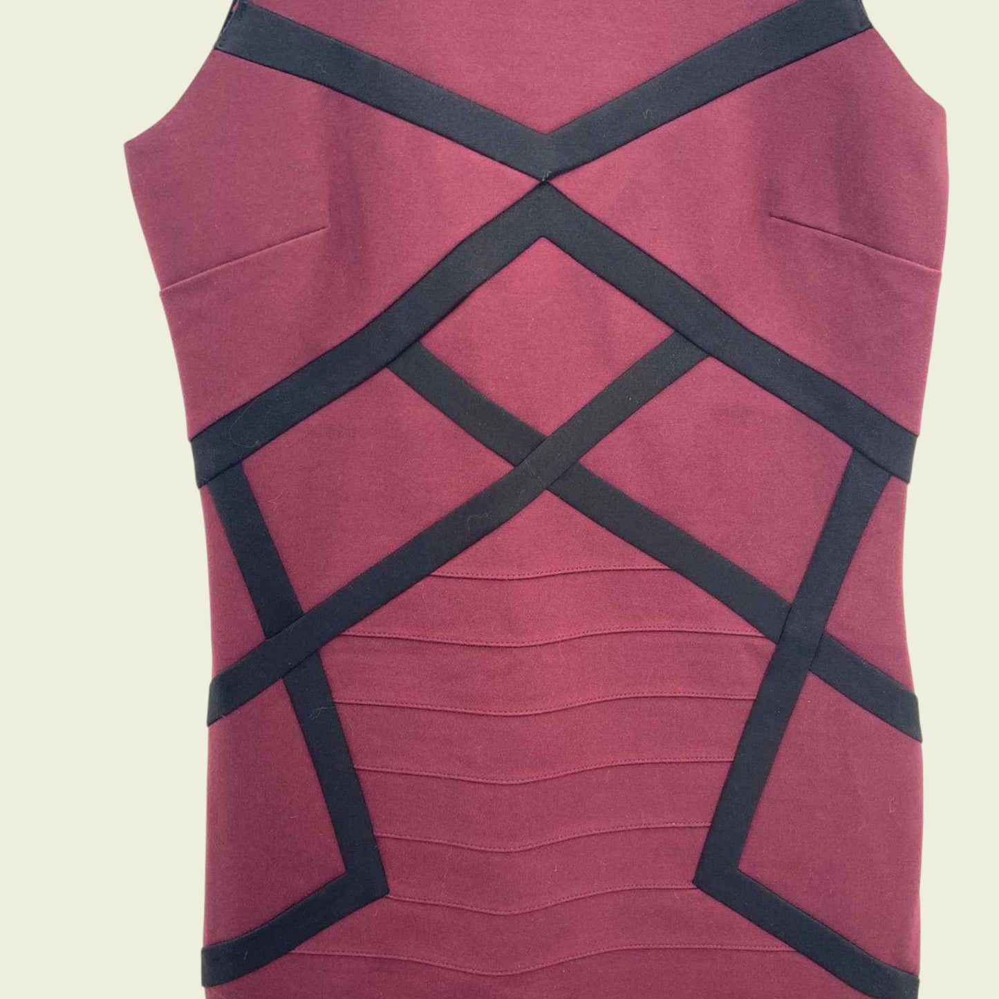 Maroon dress with black criss-cross straps on a beige background