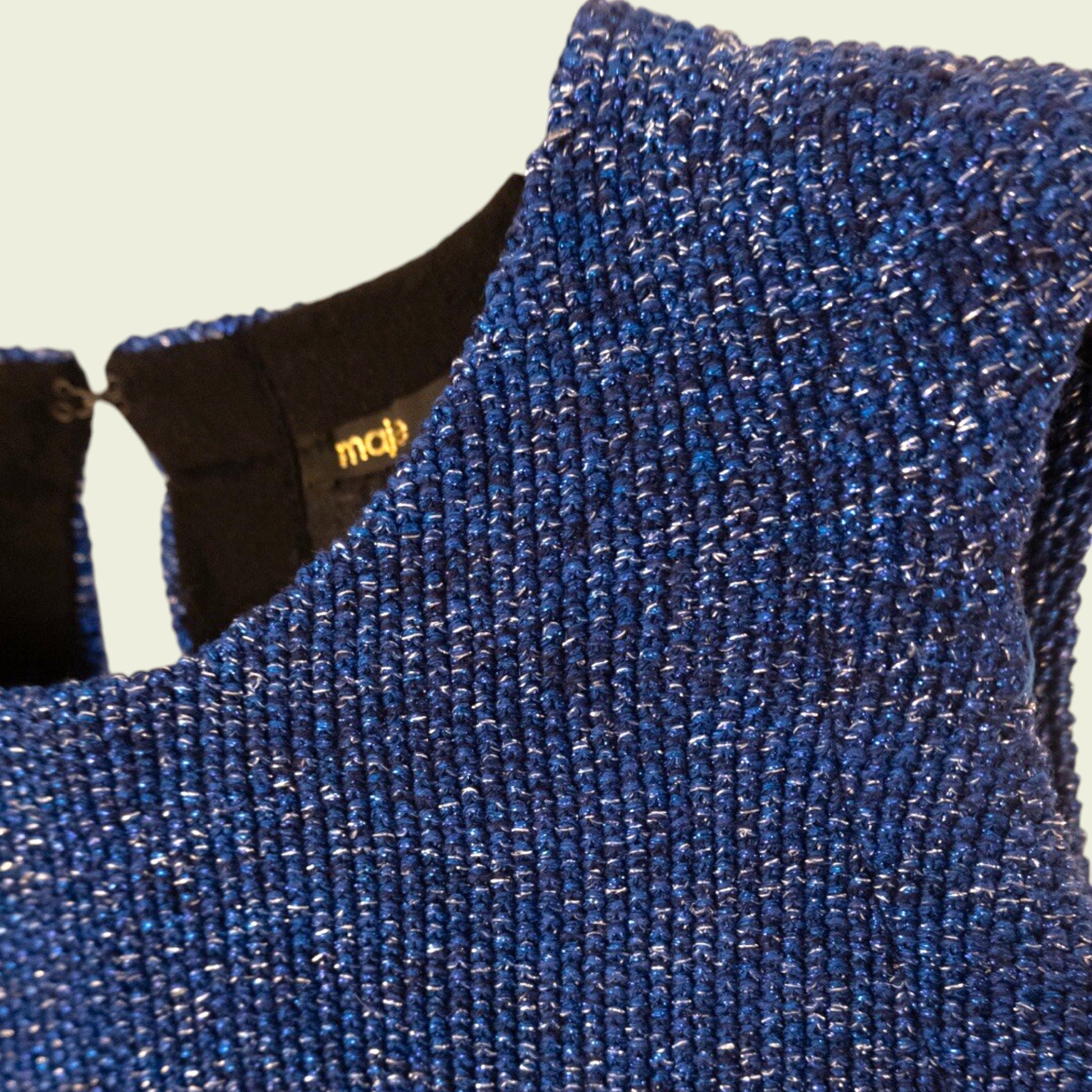 Close-up of a blue textured fabric with a brand logo on a beige background