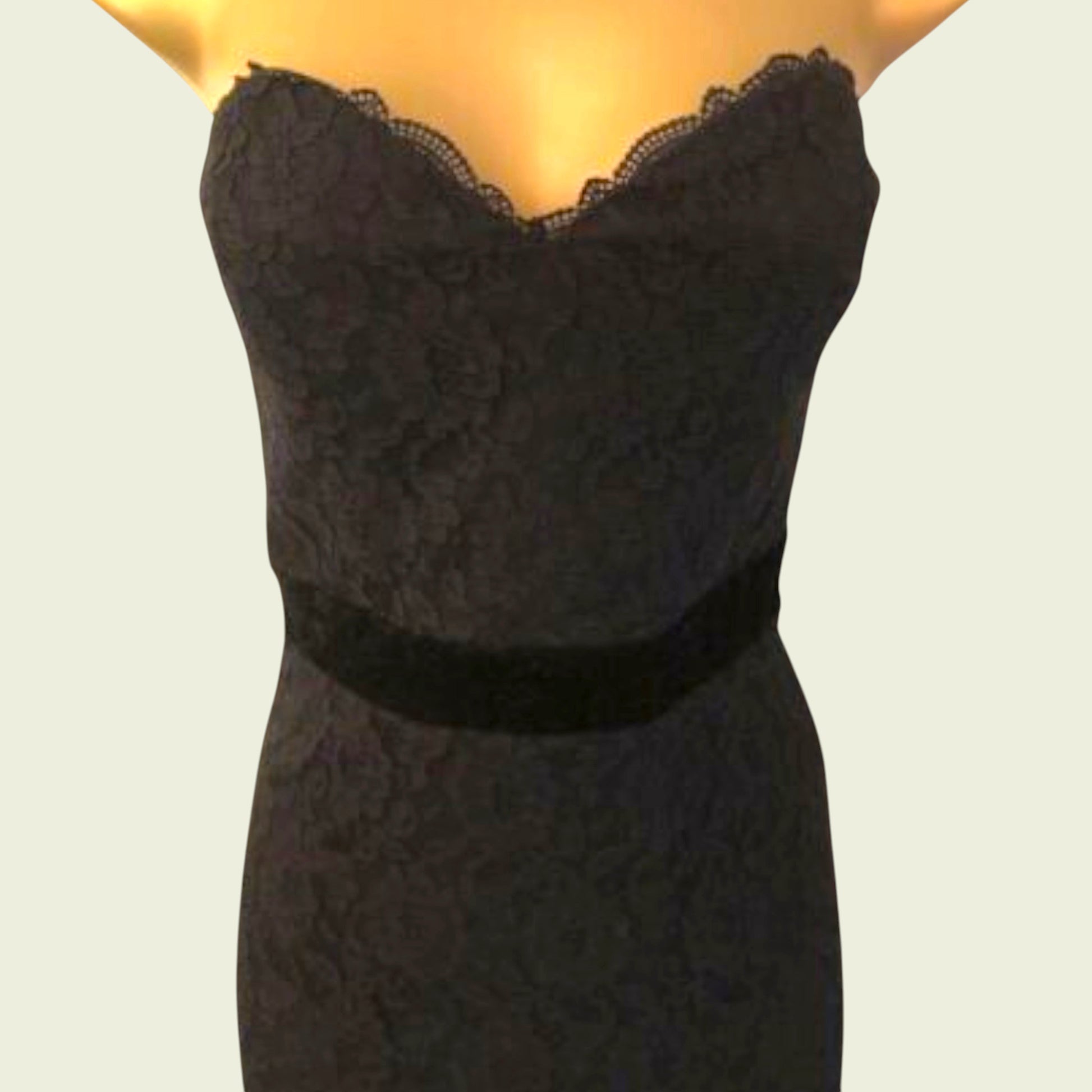 Black lace dress on a mannequin against a plain background