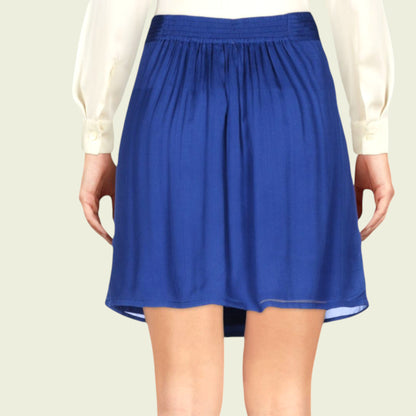 Model wearing a blue pleated mini skirt on beige background