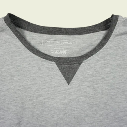 Gray shirt with black trim and visible brand logo on a beige background