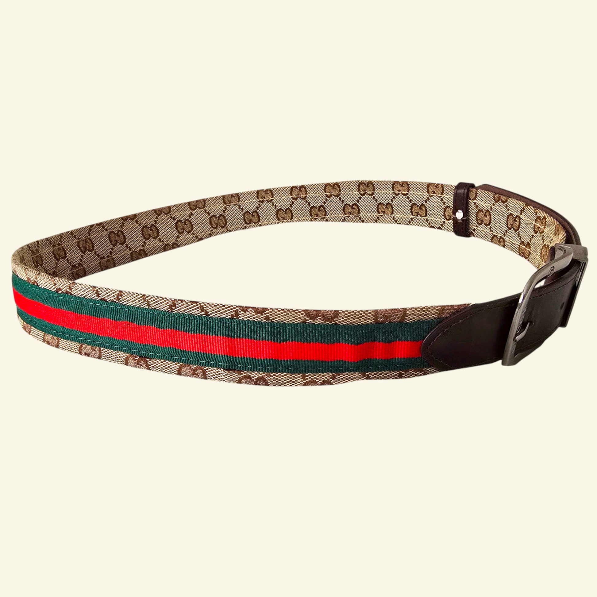 Gucci belt with brown leather strap and patterned webbing on a beige background