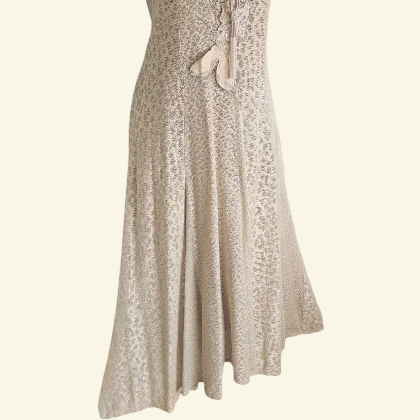 A sleeveless beige maxi dress with a textured pattern, shown against a solid cream background.