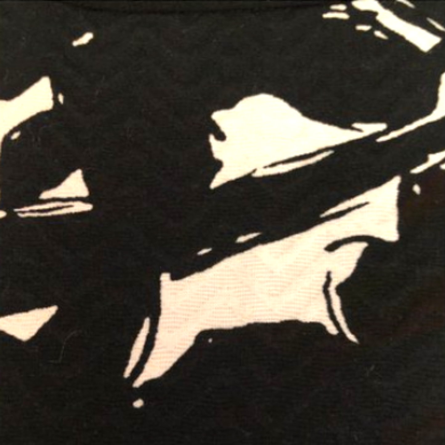 A close-up of a black fabric with a bold, high-contrast cream or off-white abstract graphic print.