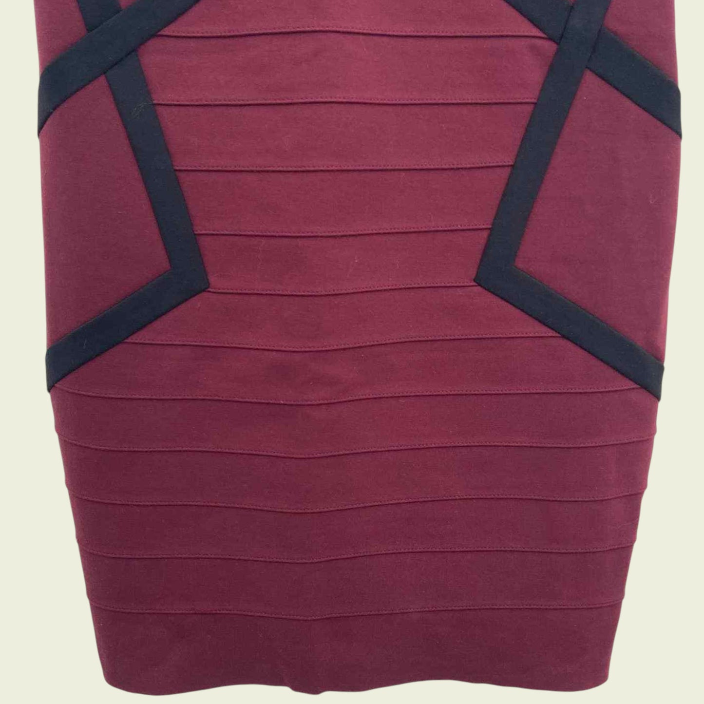 Maroon dress with black geometric accents on a beige background