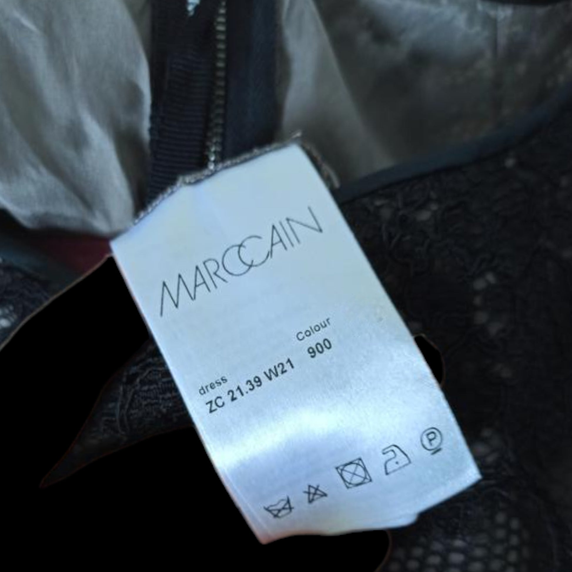 Close-up of a Marc Cain label on a garment with visible text and icons.