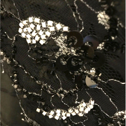 Close-up of black lace fabric with silver embellishments