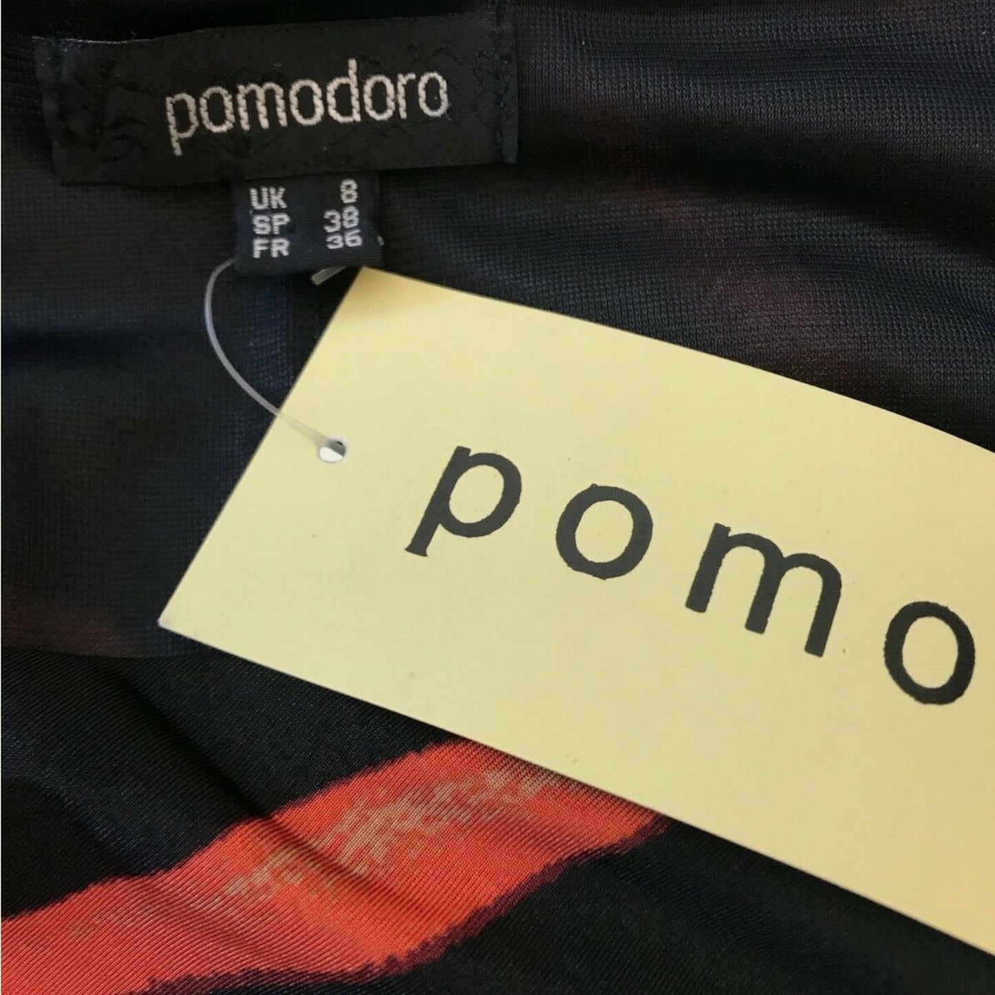 Clothing tag with 'pomodoro' brand name on a black fabric background