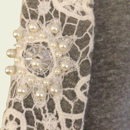 Close-up of a lace fabric with pearl embellishments on a neutral background