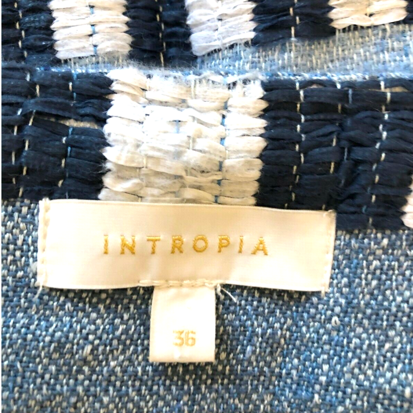 Textile with 'INTROPIA' label on a blue and white striped fabric background