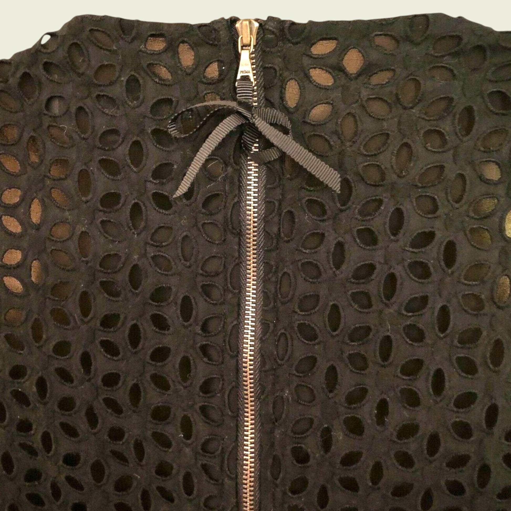 Black textured garment with a gold zipper on a beige background