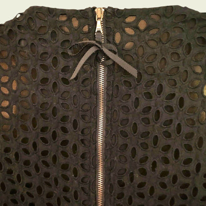 Black textured garment with a gold zipper on a beige background