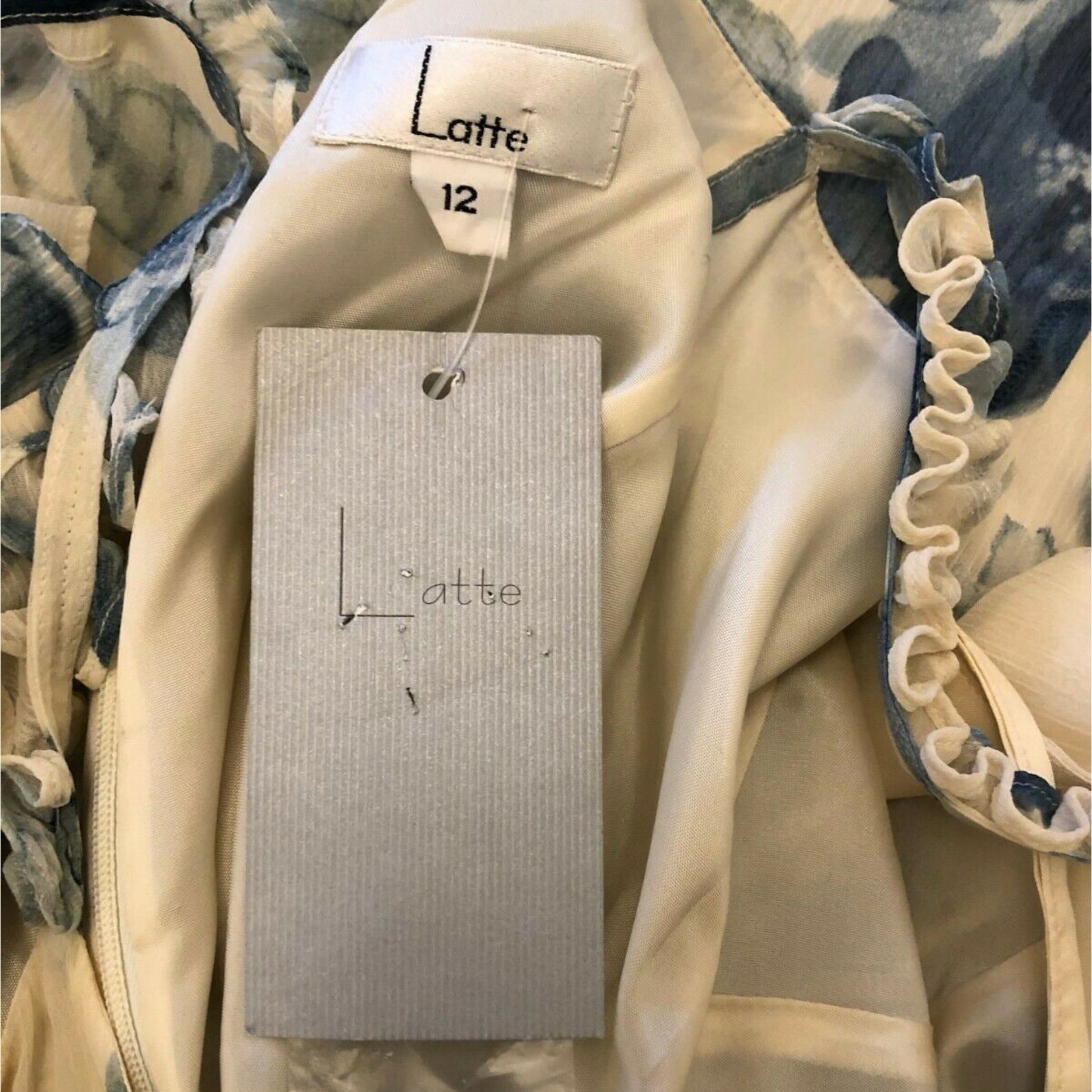 Close-up of a beige garment with a 'Latte' tag on a floral background