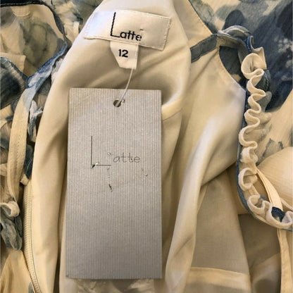 Close-up of a beige garment with a 'Latte' tag on a floral background