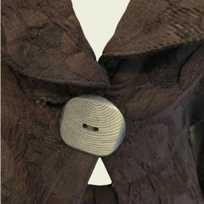 Close-up of a brown textured fabric with a button and white triangle