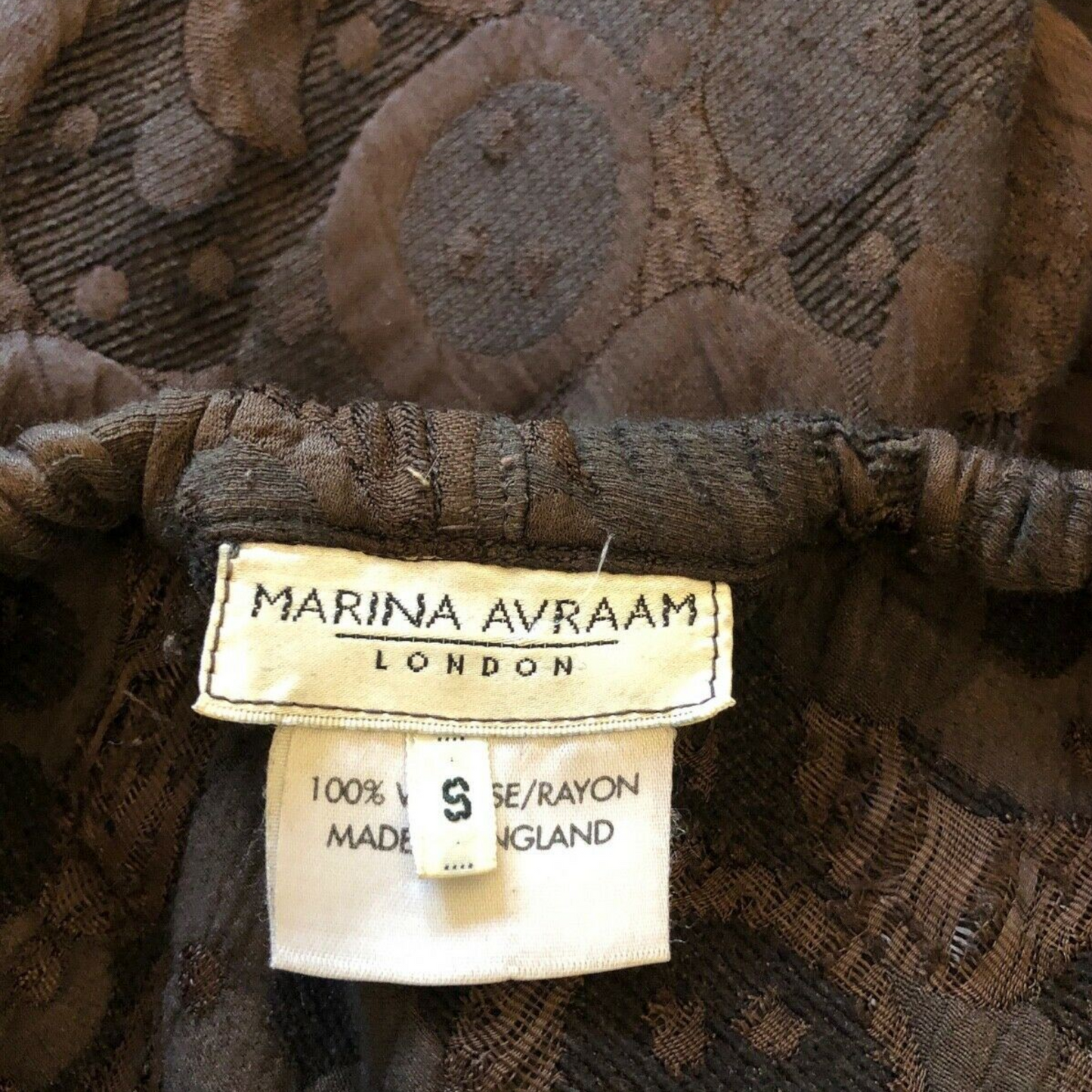 Marina Avraam London label on a piece of fabric with a patterned background