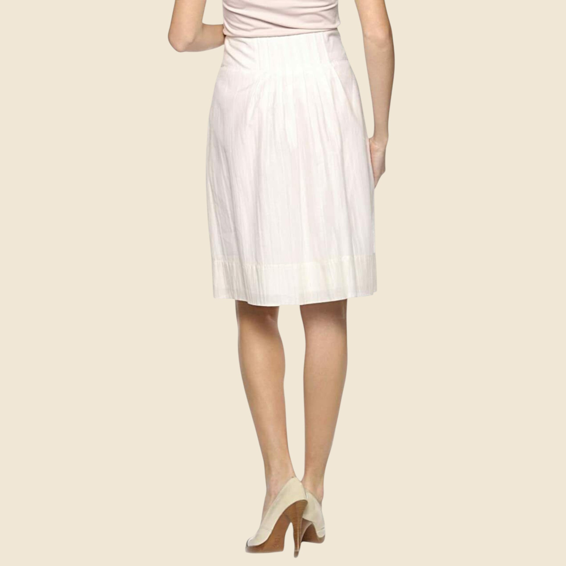 Cream pleated skirt worn by a person on a beige background