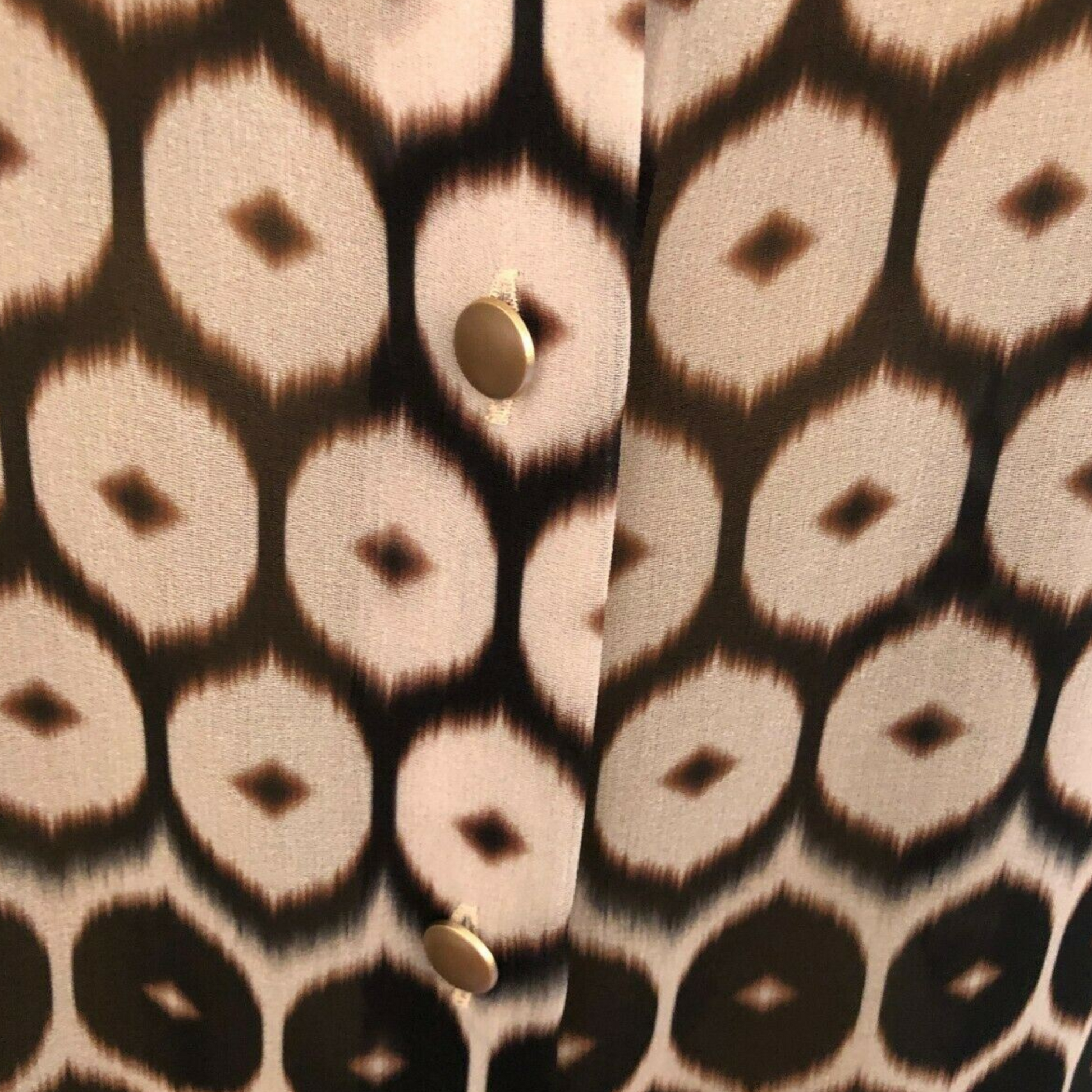 Close-up of a patterned fabric with circular designs in brown and black.