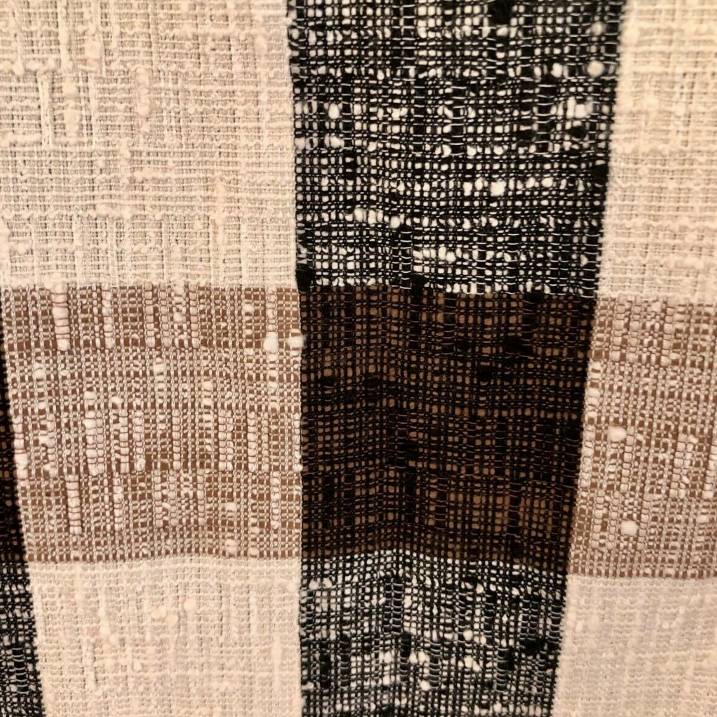Close-up of a textured fabric with a checkered pattern in brown, black, and beige.