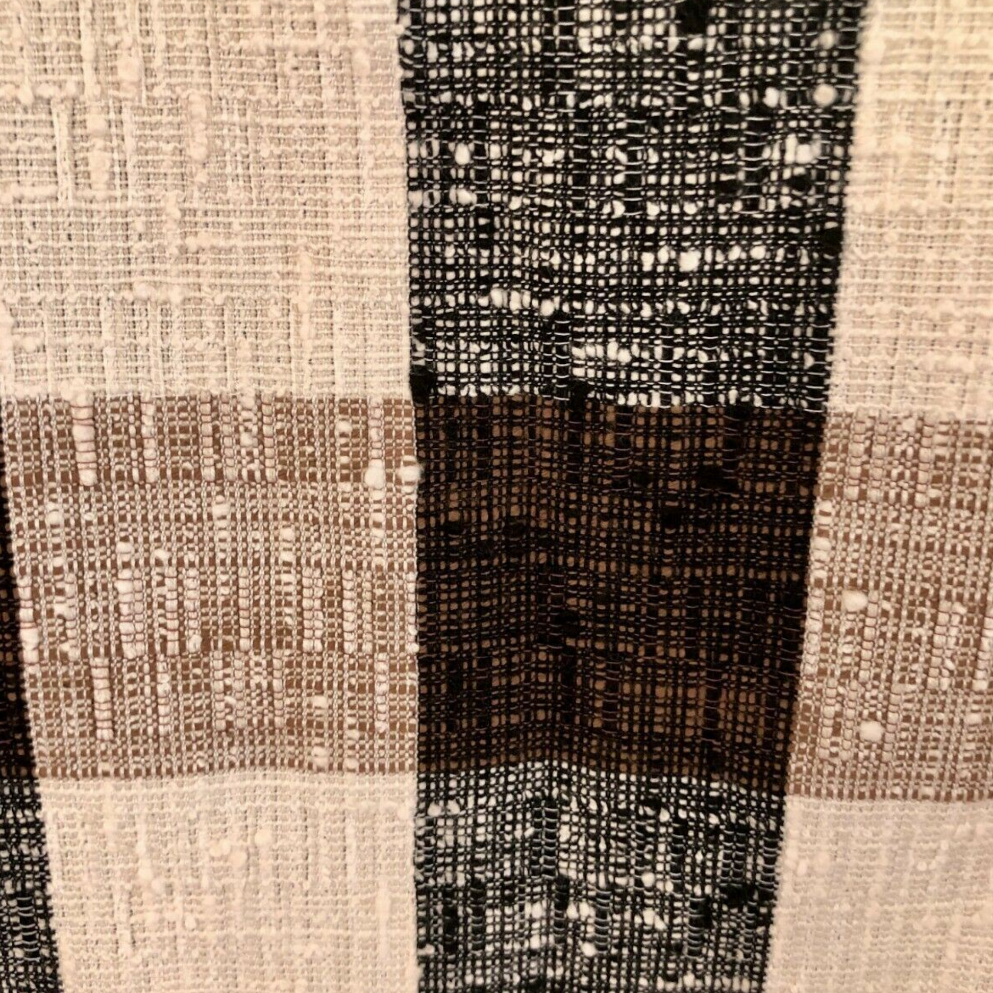 Close-up of a textured fabric with a checkered pattern in brown, black, and beige.