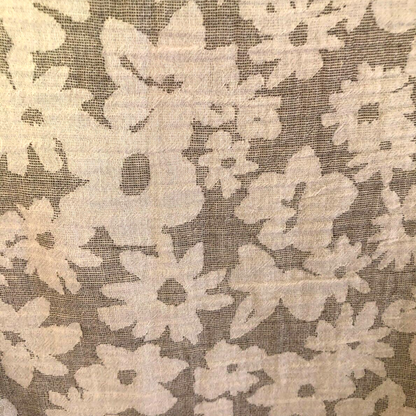 Close-up of floral lace fabric with beige flowers on a dark background