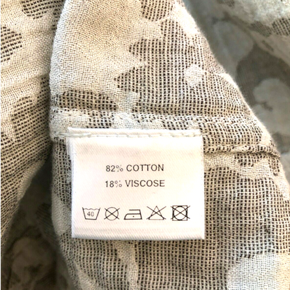 Fabric with a label indicating 82% cotton and 18% viscose, placed on a textured fabric background.