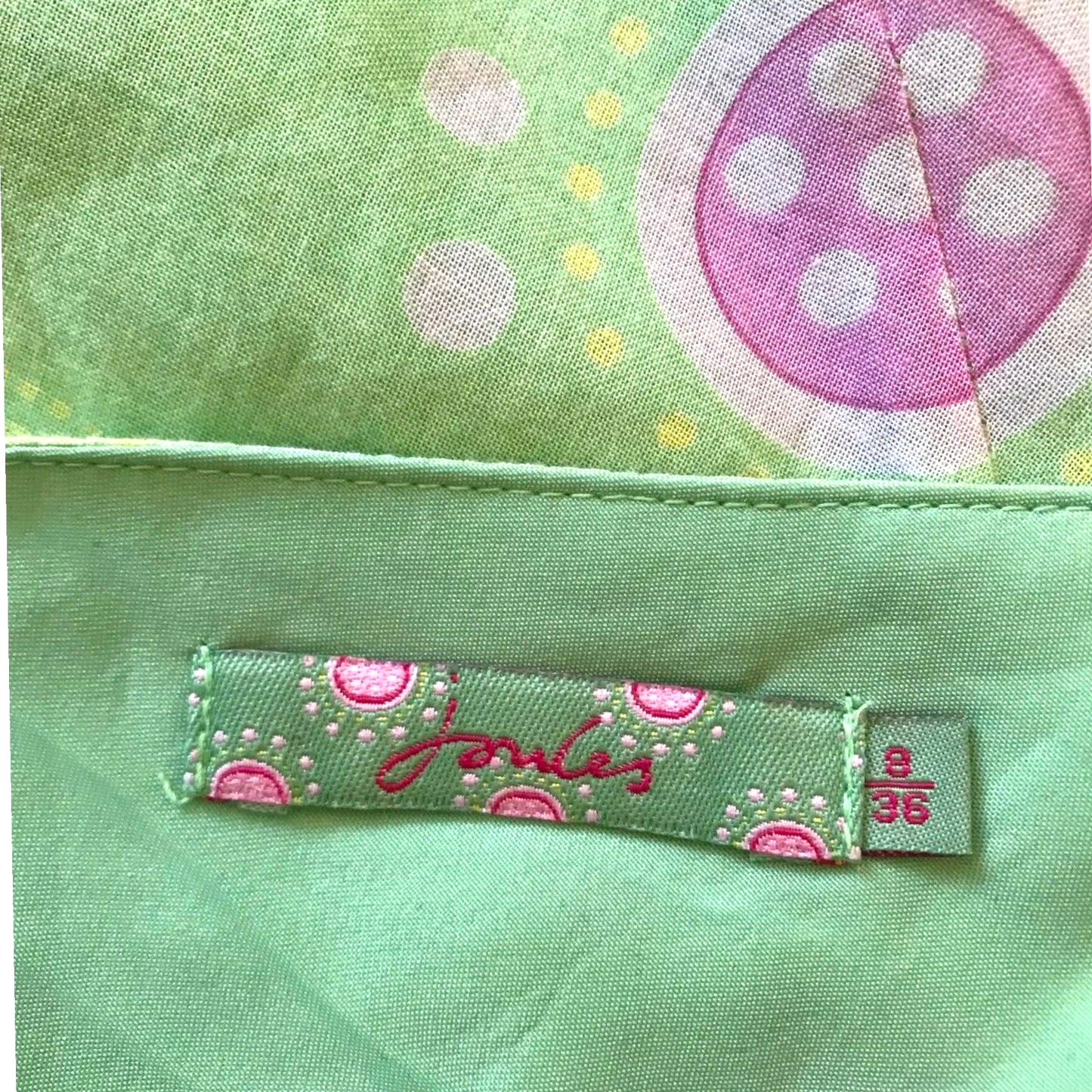 Close-up of a green fabric with a polka dot design and a label on a green background.