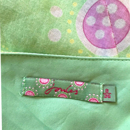 Close-up of a green fabric with a polka dot design and a label on a green background.