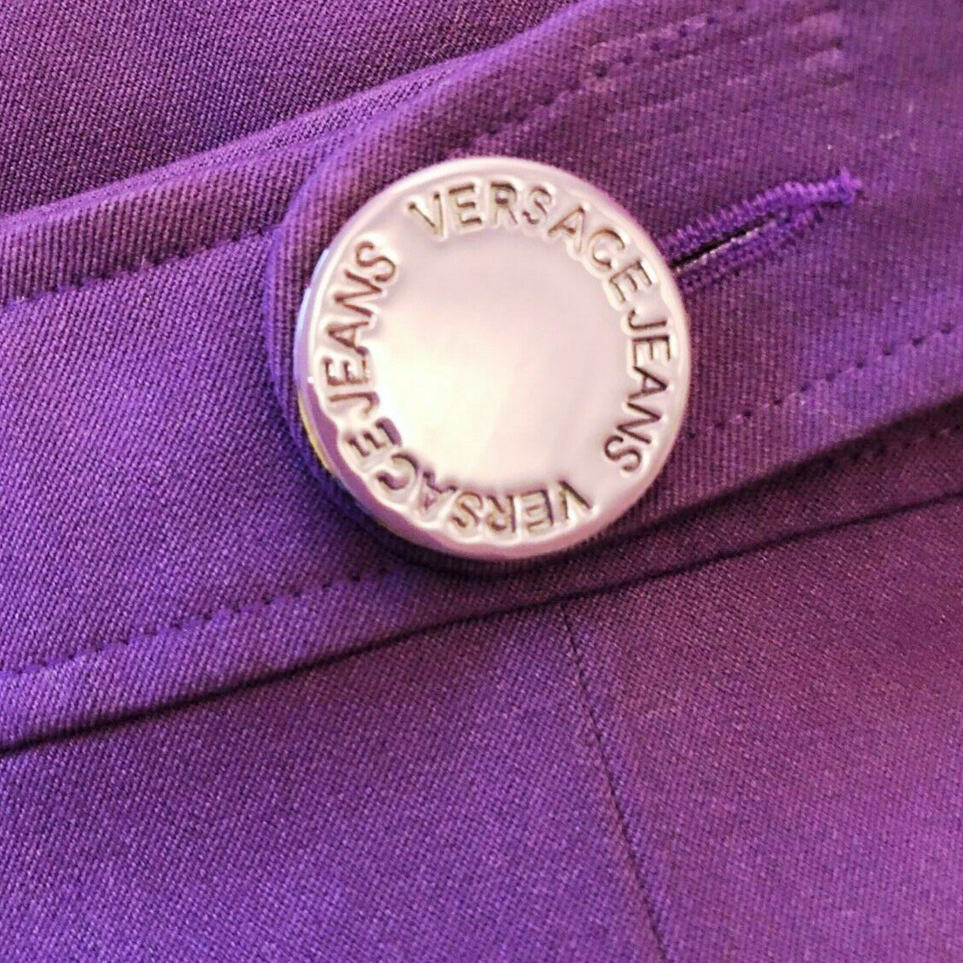 Close-up of a Versace Jeans button on a purple fabric background