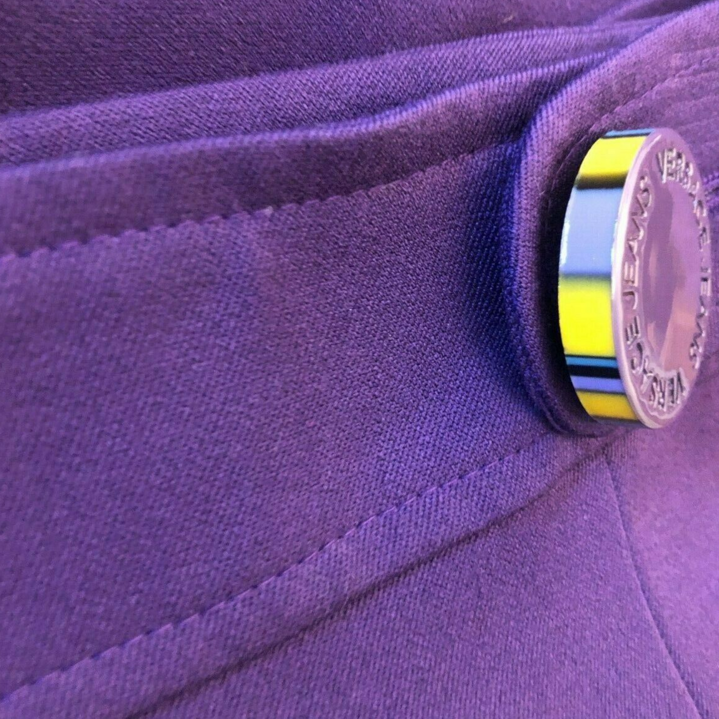 Close-up of a purple fabric with a coin partially embedded in it.