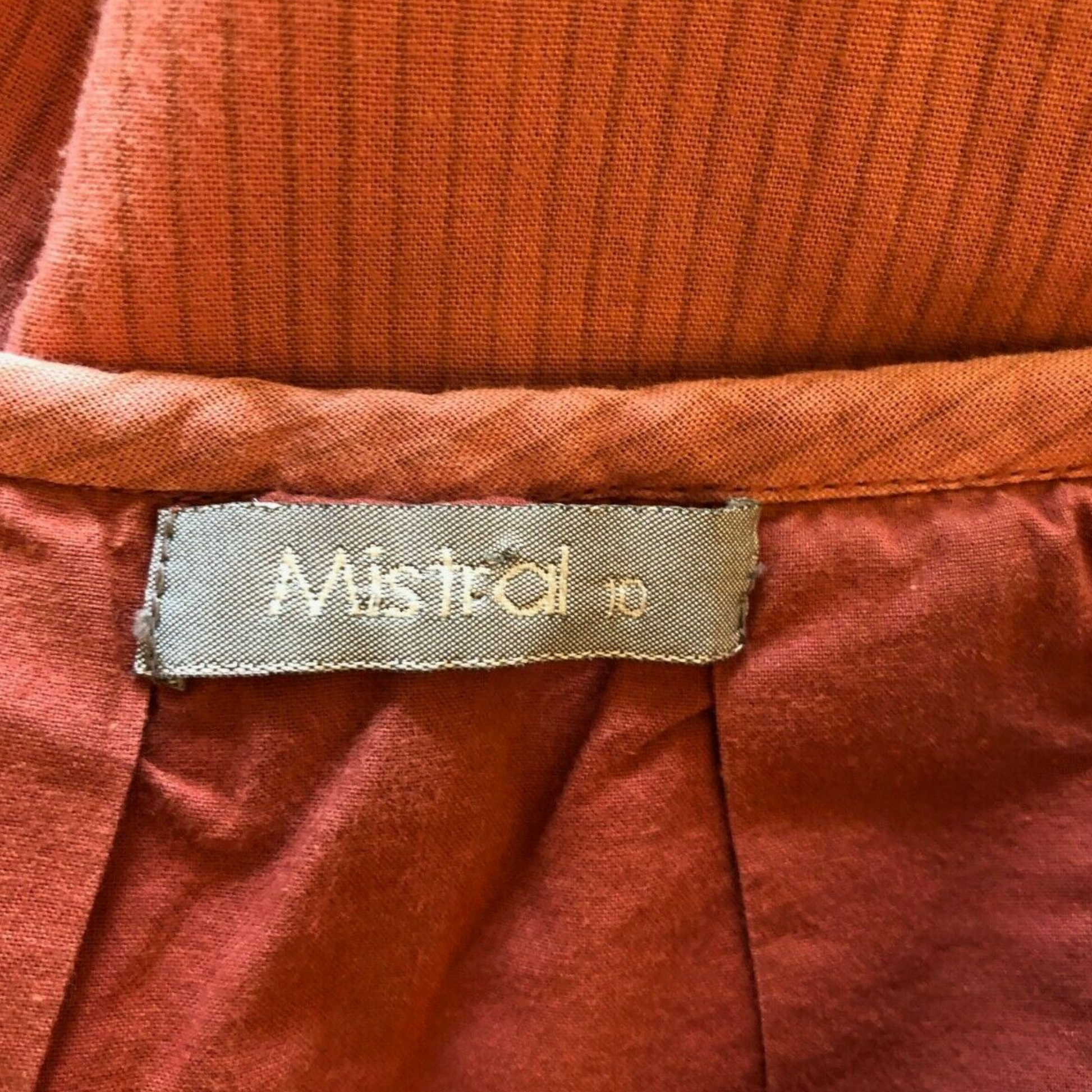 Close-up of a rust-colored fabric with a 'Mistral' label on it.
