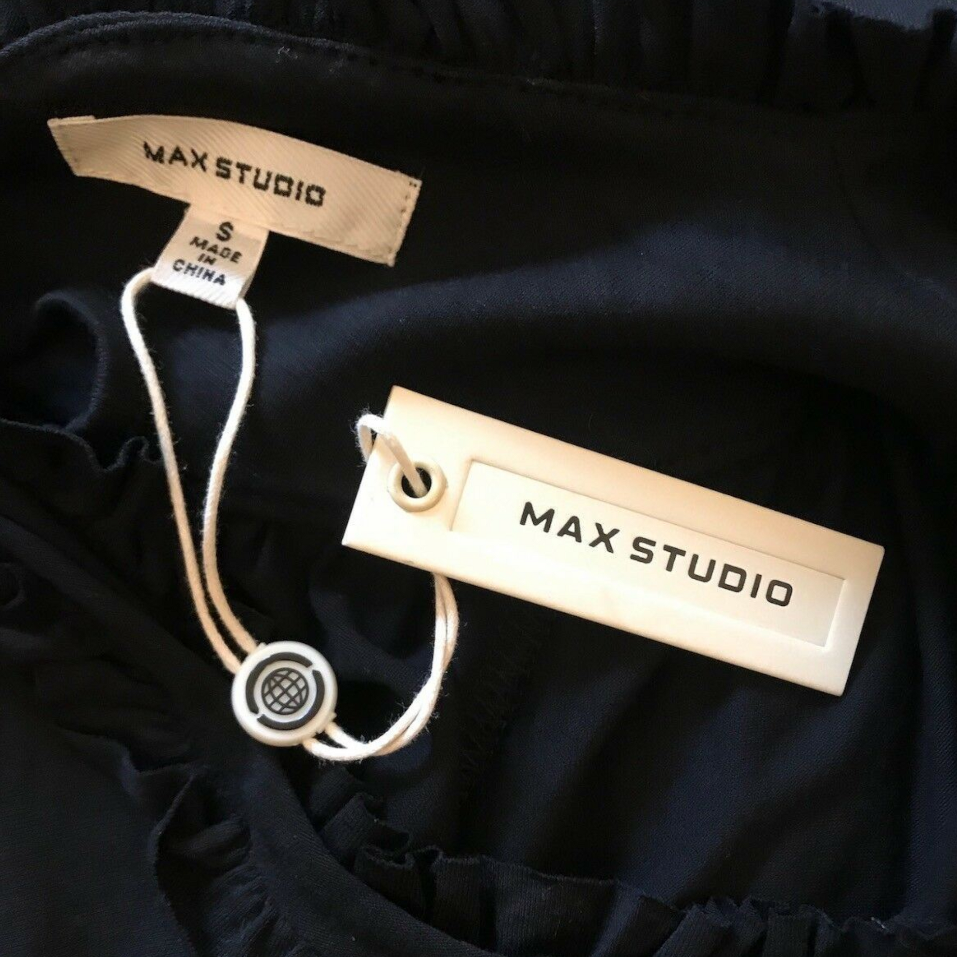 Max Studio label on a black garment with visible tag.