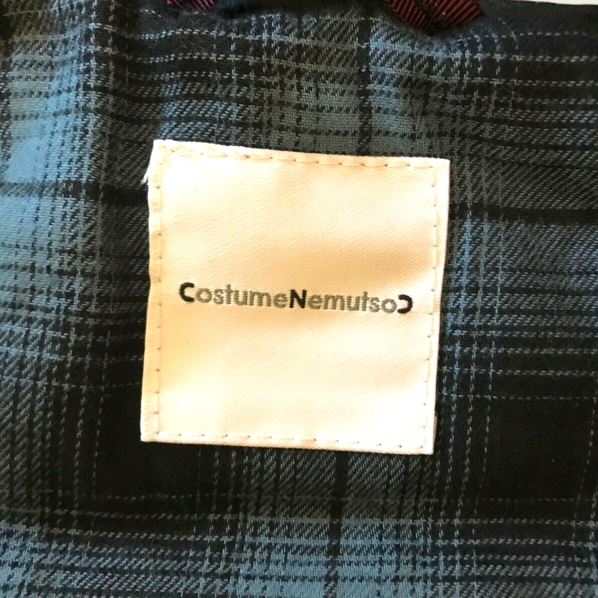 Label with 'Costume Nemutso' on a plaid fabric background