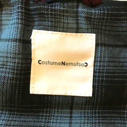 Label with 'Costume Nemutso' on a plaid fabric background