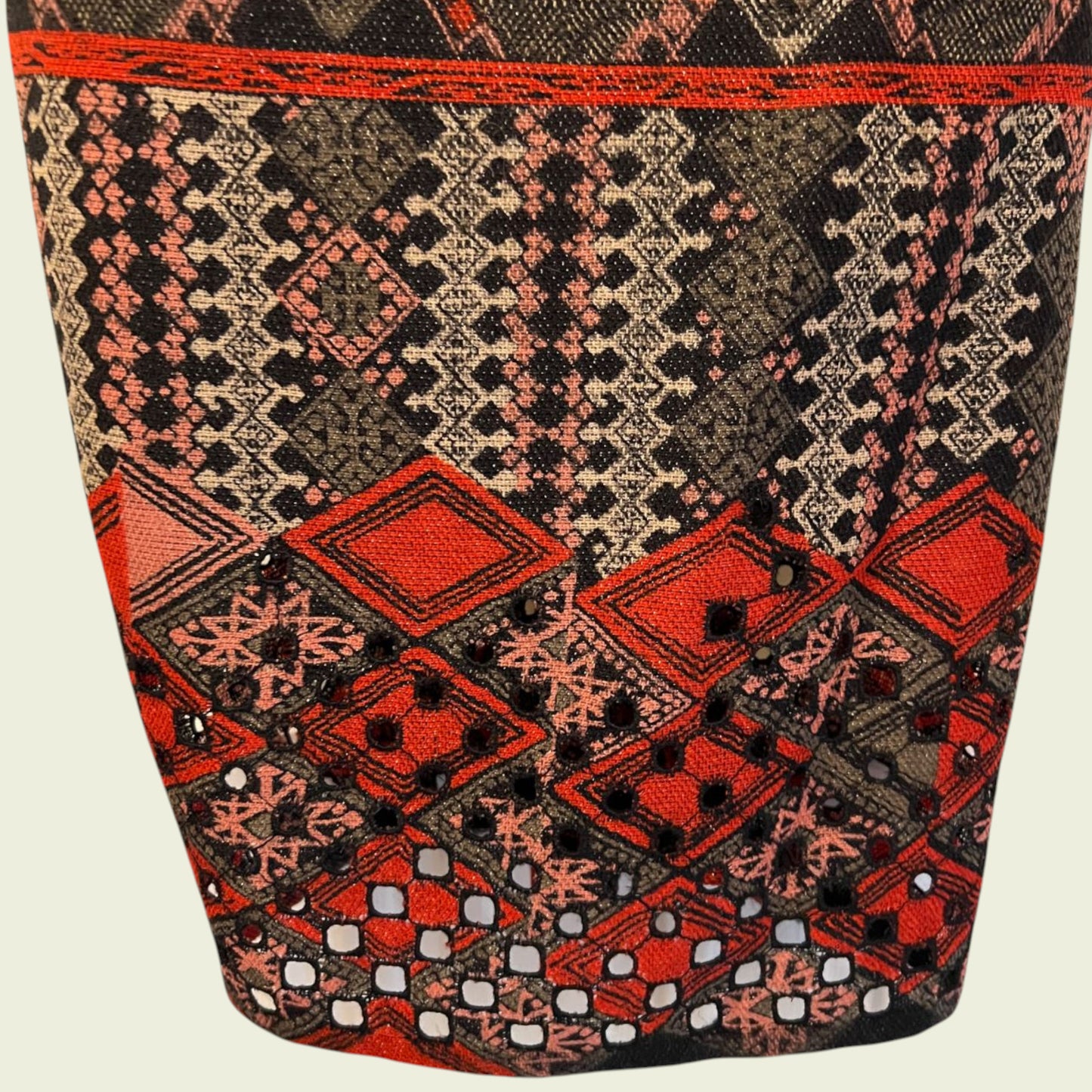 Close-up of a fabric with intricate geometric pattern in red, black, and beige on a beige background