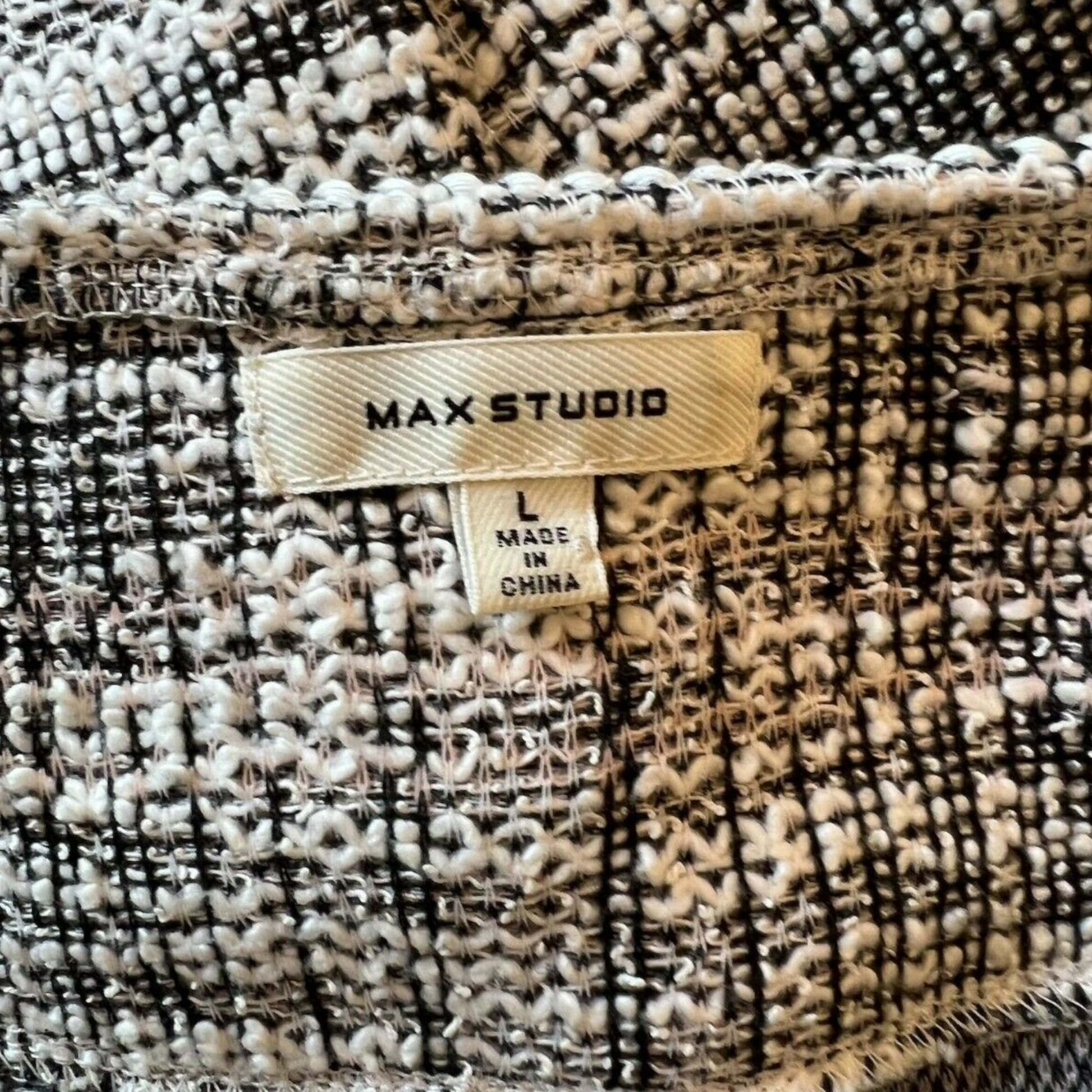 Close-up of a textured fabric with a 'MAX STUDIO' label on a garment.