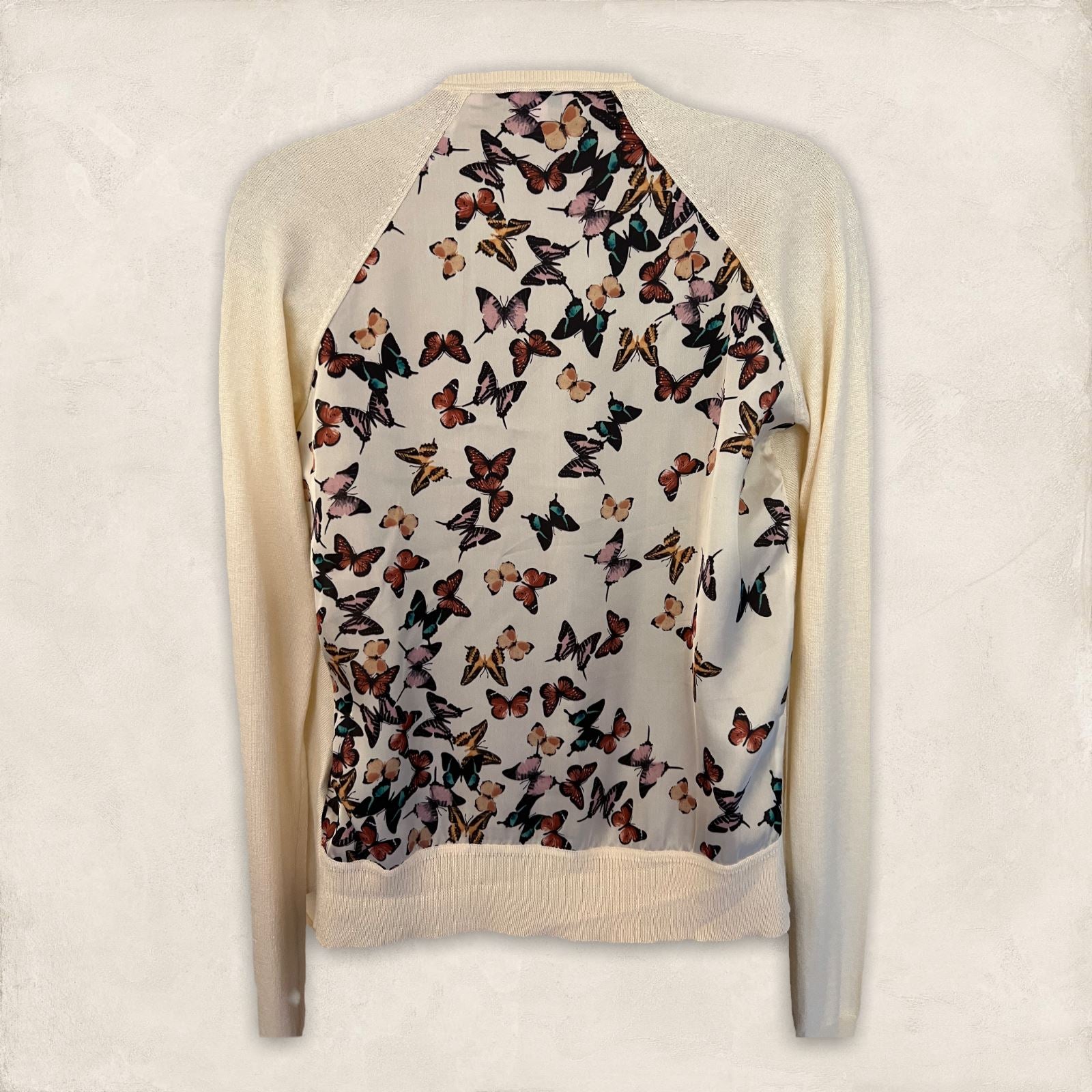 Sweater with butterfly pattern on the back against a plain background