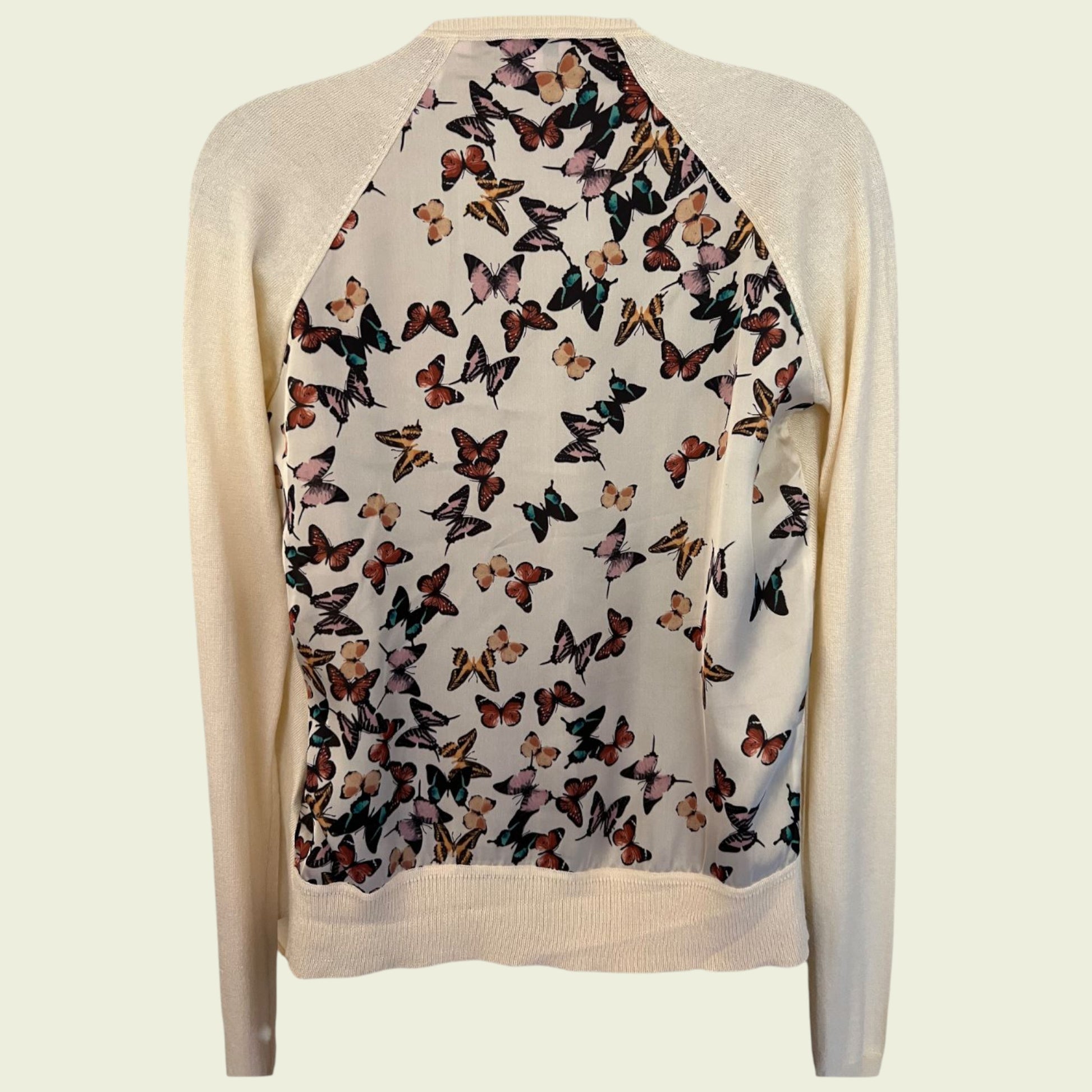 Beige cardigan with butterfly pattern on a light beige background