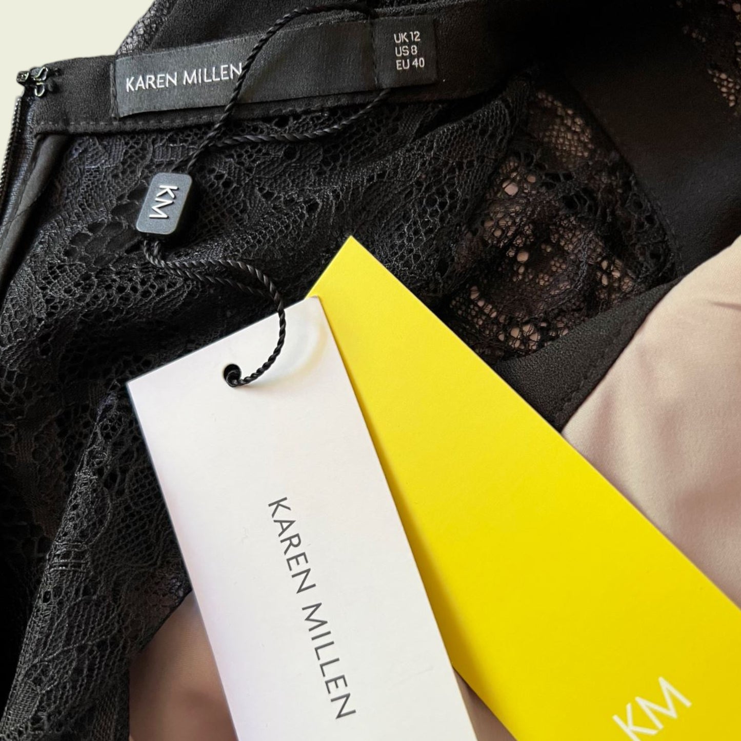 Black lace garment with 'Karen Millen' label and packaging on a blurred background