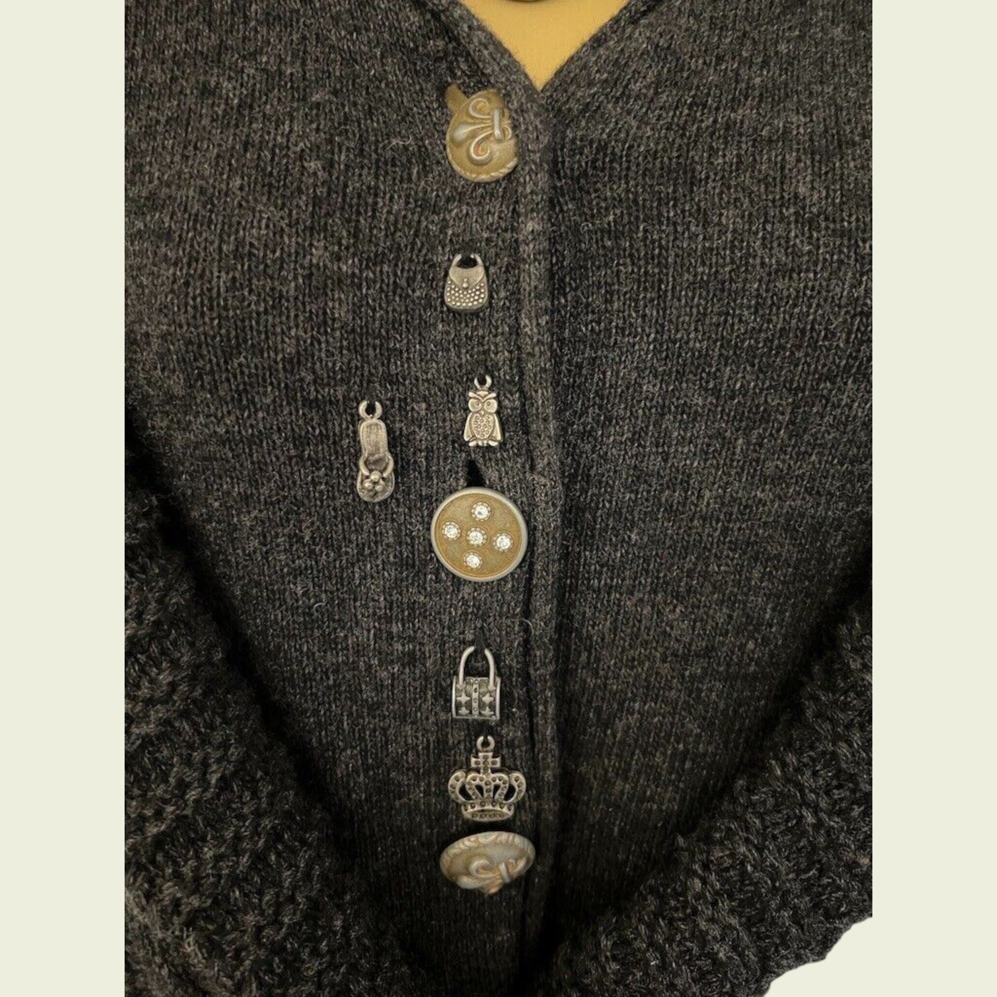 Close-up of a dark textured garment with decorative buttons on a beige background
