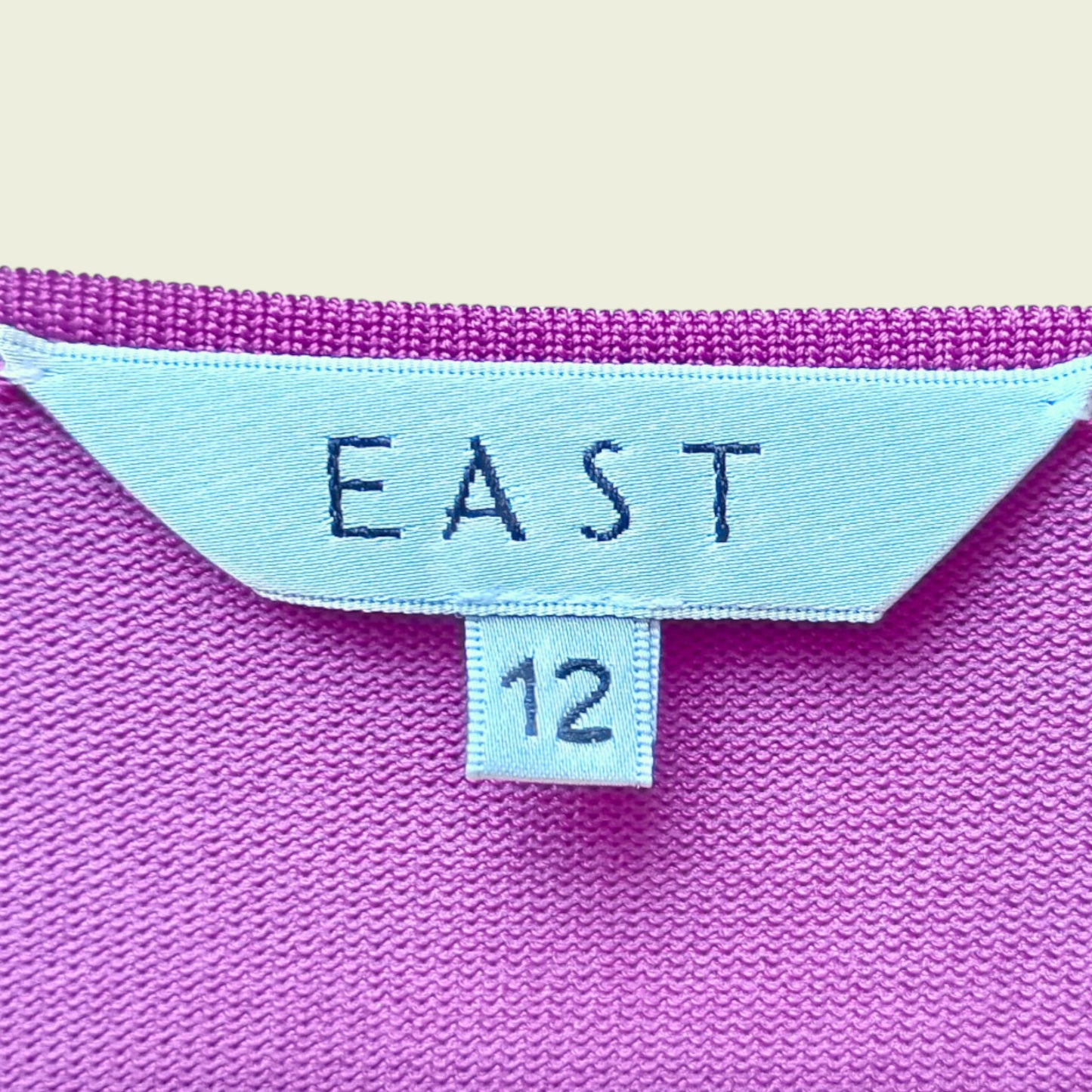Close-up of a Fuchsia pink fabric with 'EAST' and number '12' label.