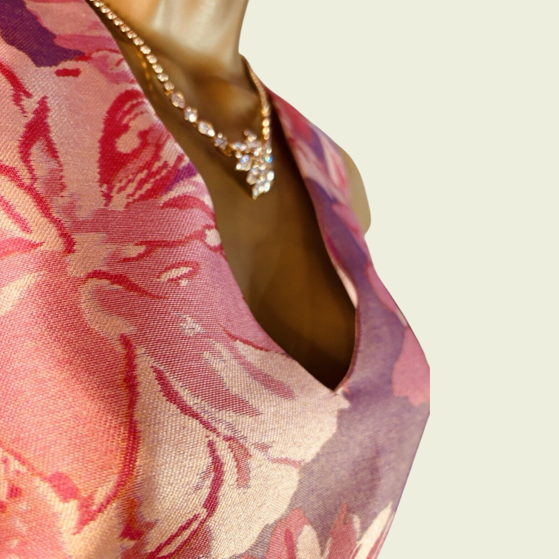 Mannequin wearing a floral dress with a necklace on a plain background