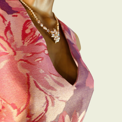 Mannequin wearing a floral dress with a necklace on a plain background