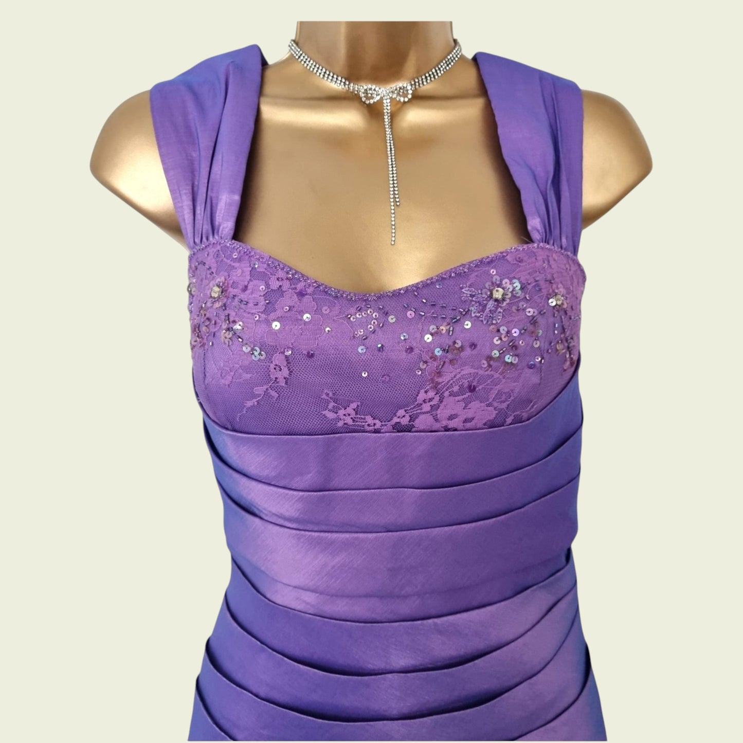 Purple dress with sequin detailing on a mannequin against a beige background