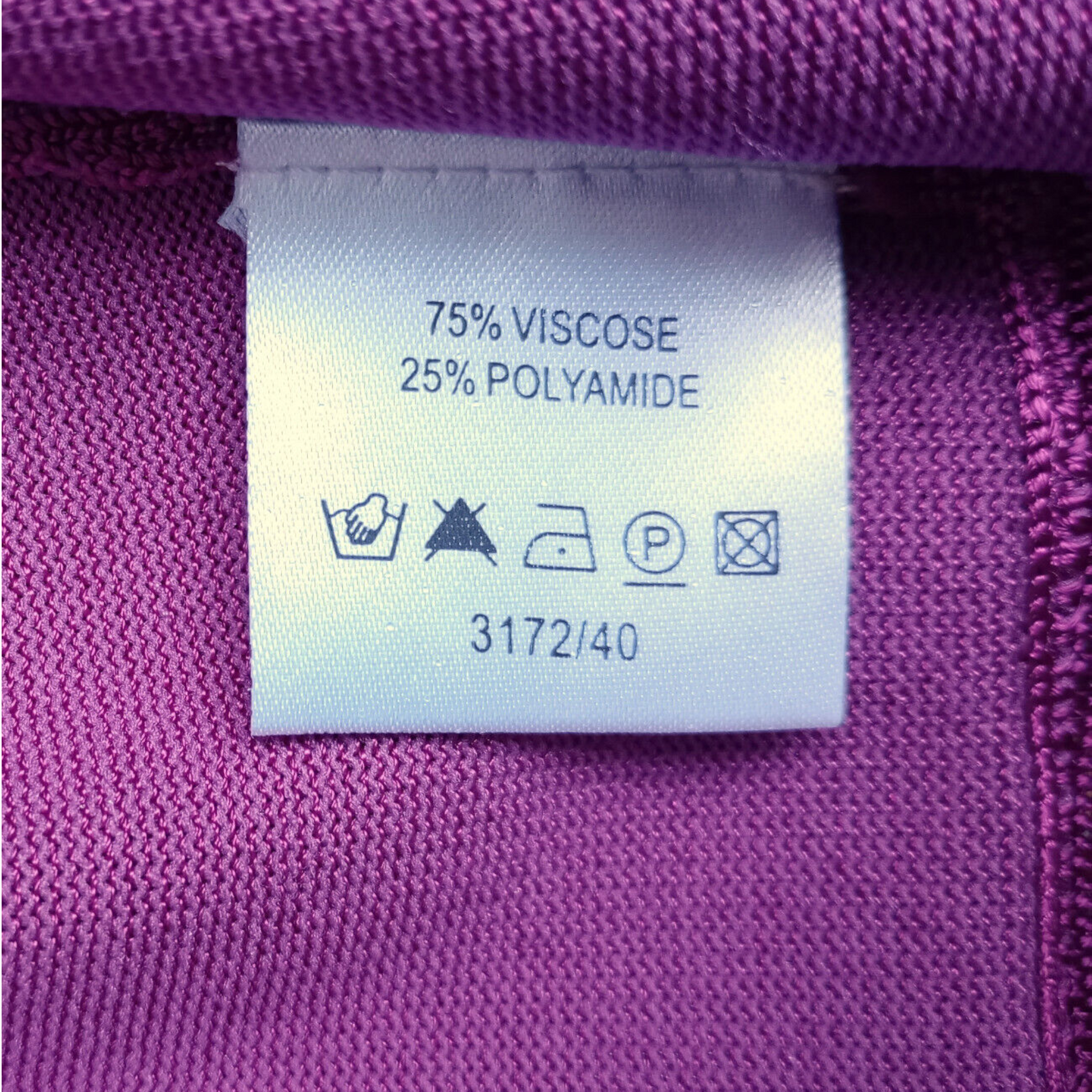 Clothing label with fabric composition and care instructions on a purple fabric background