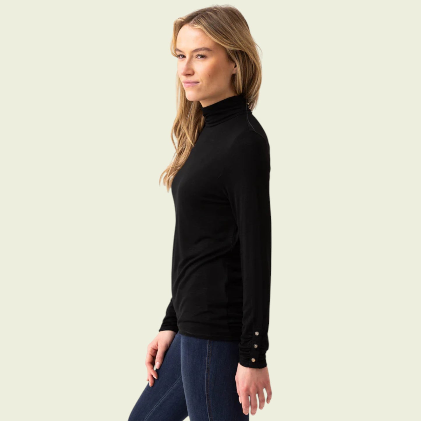 Woman wearing a black turtleneck sweater with button details on a beige background