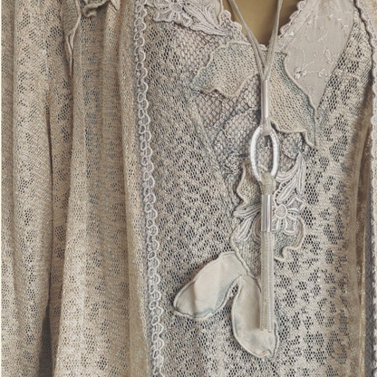 A close-up of a beige lace dress and jacket with embroidered details.